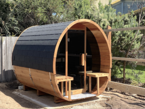 Red cedar sauna room outdoors with bright sunlight and lush green plants showcasing natural wood design and relaxing ambiance
