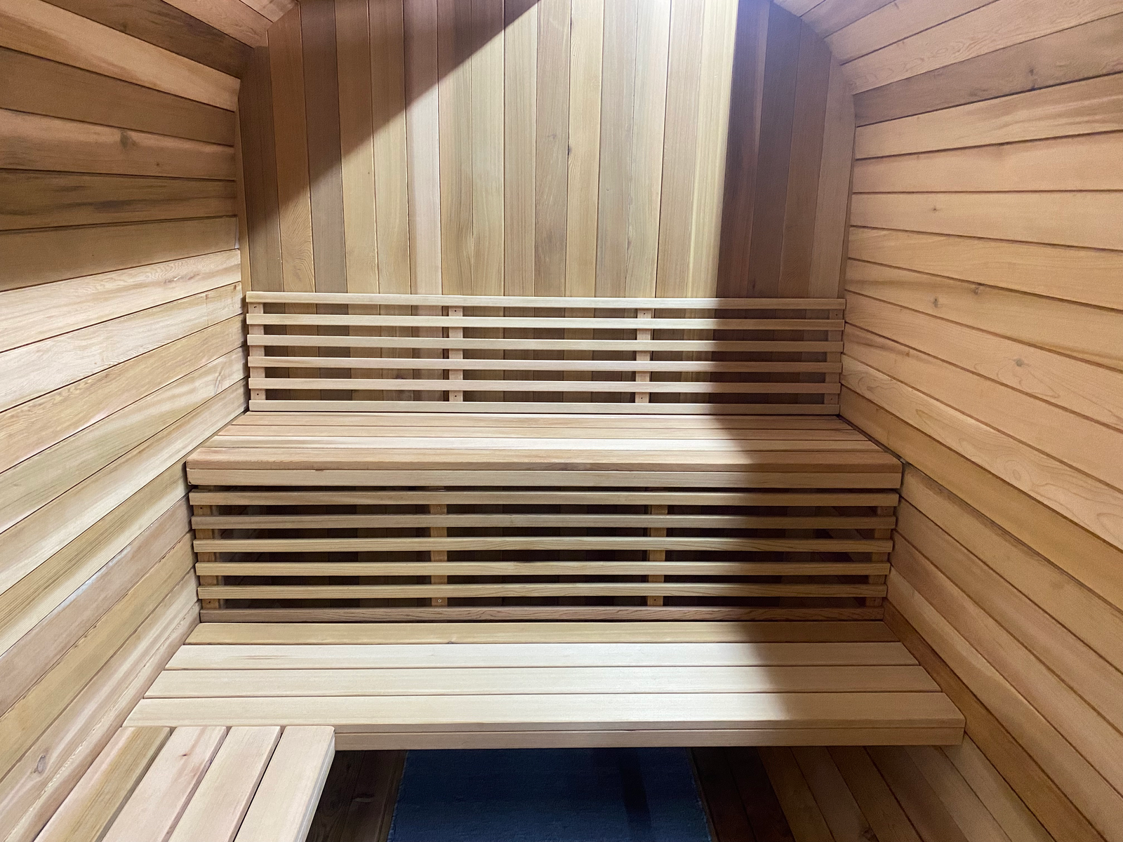 Interior of square red cedar sauna with neatly arranged benches and backrests