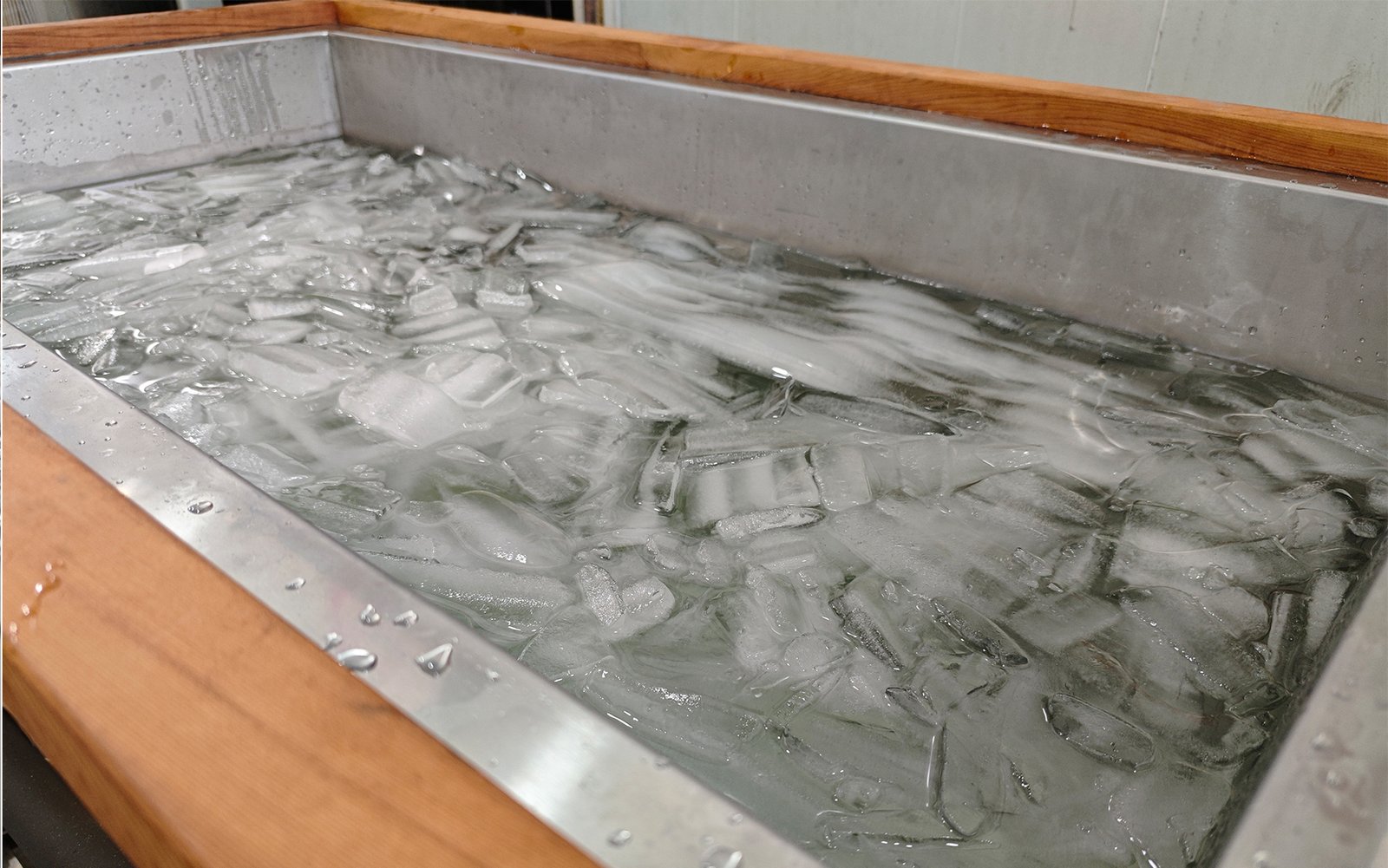 Ice bath tub with stainless steel interior filled with ice water and floating crushed ice on the surface