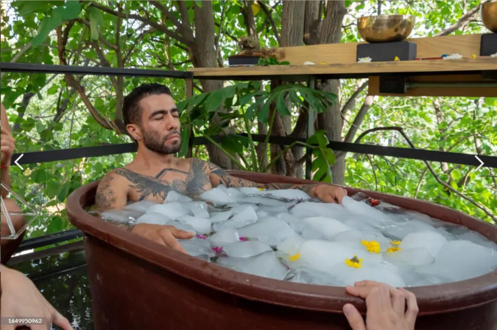 A man immersed in an ice bath for recovery, with visible ice cubes in the water.