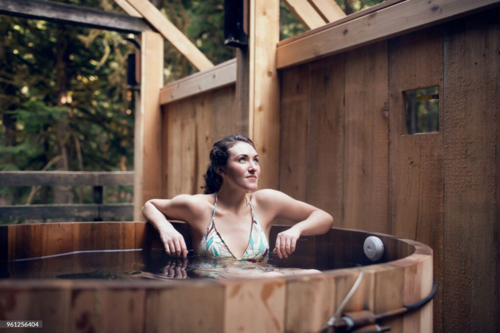 A person unwinding in a hot tub, enjoying a serene and relaxing soak under the open sky.